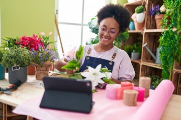 Poster - African american woman florist make bouquet of flowers watching video on touchpad at flower shop