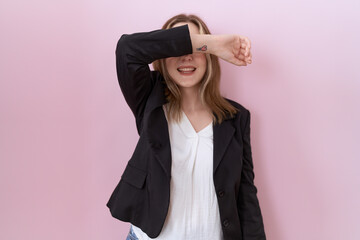 Canvas Print - Young caucasian business woman wearing black jacket covering eyes with arm smiling cheerful and funny. blind concept.