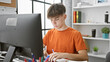 © Krakenimages.com - Focused teenage boy studying at a modern home desk setup, with a computer and notebooks