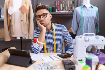 Hispanic man with beard dressmaker designer working at atelier thinking looking tired and bored with depression problems with crossed arms.