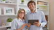 © Krakenimages.com - Smiling man and woman, two confident workers enjoy their job, together at office using touchpad gadget, happiness amidst professional success