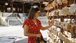 © Krakenimages.com - Portrait of a beautiful hispanic woman in glasses at japan's iconic meiji temple, affectionately admiring the japanese wooden ema prayer boards and soaking in the rich traditional culture