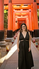 Sticker - Gorgeous hispanic woman in glasses flaunting a radiant smile at the majestic torii gates of fushimi inari-taisha, kyoto