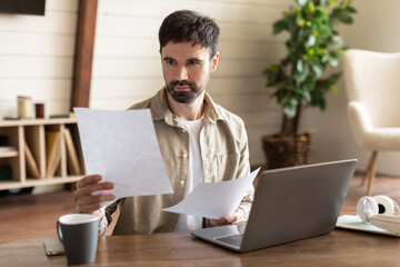 Aufkleber - A man is seated at a table, working on a laptop and surrounded by papers. He appears focused and engaged in his work, possibly studying, researching, or writing
