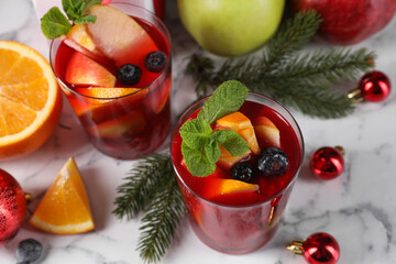 Wall Mural - Aromatic Sangria drink in glasses, ingredients and Christmas decor on white marble table