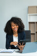 © NanSan - A young African American woman in a blue formal shirt with afro brown hair works as a product designer in a modern office, utilizing skills in design, CAD, CNC, and CNF.