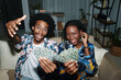 Joyful young Black couple posing with playing cards at home