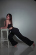 © Velychko - Portrait of a beautiful fashion model in the studio on a light background, wearing a black short clothes and trousers, barefoot