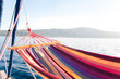 Beach hammock by lake. Relaxation on yacht at sea in summer vacation. Rest on holidays. Concept of slowing down, deceleration, enjoying nature, slow living. Transformational and ecological travel