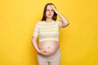 Unhealthy beautiful young pregnant woman wearing striped top posing isolated over yellow background touching painful head grimacing from pain suffering migraine during pregnancy