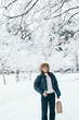Traveler with Sweater and backpack walking on snow covered forest in frosty weather. Winter Travel, Adventure, Exploring and Vacation concept