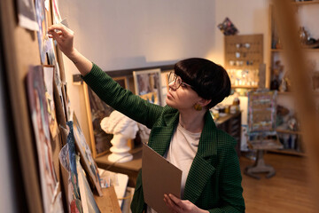 side view portrait of female artist painting oil painting on easel in art studio, copy space