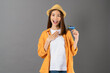 Happy cheerful young woman standing and holding credit card on grey background.