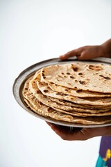 Wall Mural - closeup view of hands holding chapati or nan in plate, ready to be served.