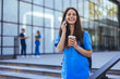 A cheerful female nurse smiles as she talks on her smartphone as she walks to work in a city medical building. After work. Nurse Using Her Mobile Phone While Taking a Break.