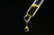 Dripping tincture from pipette on black background, closeup. Space for text