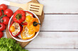 Delicious stuffed peppers in bowl, ingredients and spatula on white wooden table, flat lay. Space for text
