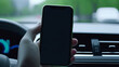 smartphone held by hand inside a moving car, presenting setting perfect for navigation or travel app promotions. The blurred dashboard and road in the background