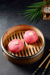 Pink bao buns shaped like pigs in a bamboo steamer; a playful and appetizing Asian culinary creation