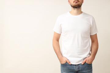 Wall Mural - A young guy in a white T-shirt on a light background
