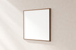 Blank square frame on a textured plain wall, casting a soft shadow, giving a minimalistic aesthetic, 3d render.
