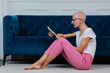 Hairless young woman challenging cancer read a book on tablet