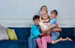 Mother challenging cancer smile, hug her three kids sit on sofa