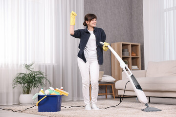 Poster - Happy young housewife having fun while cleaning carpet at home