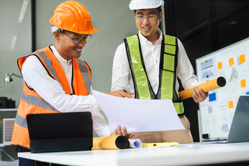 Wall Mural - Architects or engineer holding pen pointing equipment architects on laptop with on on architectural project at construction site at desk in office.