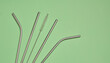 Metal straws for cocktails and a cleaning brush on a green background