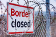 Border closed warning sign on a fence with barbed wire. Concept of illegal immigration control and no entrance.