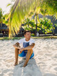 Young guy relaxing and sitting on beach. Slim man vacation on paradise beach