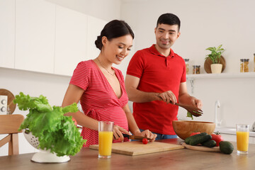 Sticker - Happy young pregnant couple cooking in kitchen