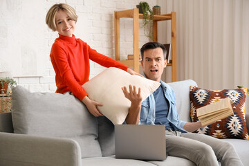 Wall Mural - Young man stressed of his naughty little son with pillow at home