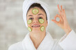 cheerful happy beautiful girl applying facial mask of cucumber