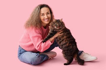 Wall Mural - Mature woman with cute cat sitting on pink background