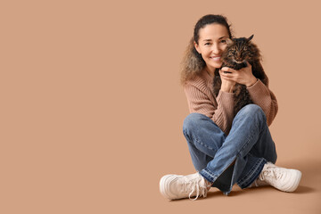 Wall Mural - Beautiful mature woman with cute cat sitting on brown background