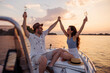 Couple having fun sailing on a boat and drinking champagne while on summer vacation