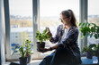 An attractive Caucasian woman identifying a green plant using an application in Smartphone. Caring for indoor plants concept