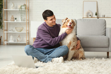 Poster - Young man with Australian Shepherd dog and laptop at home