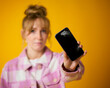 Woman Holding Damaged Mobile Phone With Cracked Screen Against Yellow Studio Background