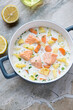 Serving pan with finnish traditional salmon soup on a light-grey granite background, high angle view, vertical shot