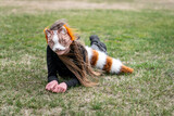 Fototapeta Przestrzenne - Teenage girl with cat mask and gloves doing Quadrobics. girl in a cat mask is lying on the grass.