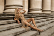 Elegant, stylish woman in sexy Macrame bikini and golden high heels is sensually walking in the city on a sunny summer day. Outdoor shoot.