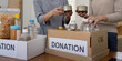 © Natee Meepian - Group of volunteer woman working in home. Happy volunteer looking at food donation box separating donations stuffs