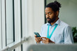 © Drazen - Black businessman text messaging on cell phone in office.
