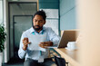 © Drazen - Black entrepreneur analyzing business reports while working in office.