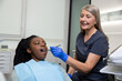 Long-haired mature dentist working on tooth restoration of a female patient