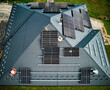 Aerial top view of new modern cottage with solar PV panels system on roof. Installation of solar batteries by two professional workers. Modern resources of electrical energy.