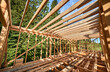 Residential wooden frame building in progress near a forest. Start of new construction of comfortable house. The idea of modern ecological building techniques and contemporary architecture.